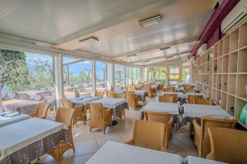 un restaurante con mesas, sillas y ventanas en Hotel Galvani, en Torri del Benaco
