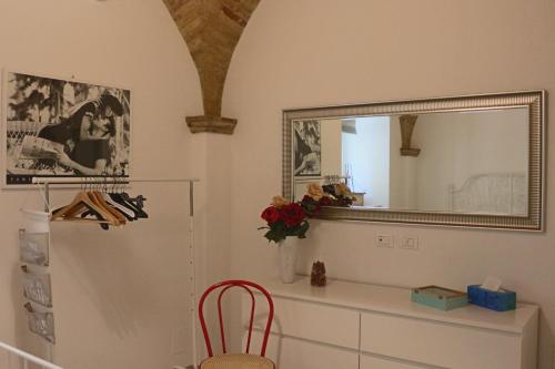 um espelho numa cómoda com um vaso de flores e uma cadeira em LA CASETTA DI LULÚ em Rocca San Giovanni
