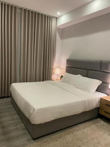 1 dormitorio con 1 cama grande con sábanas blancas en Rose 3 en Al Khobar