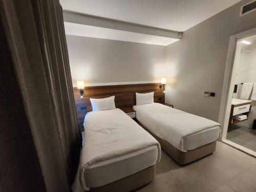 a hotel room with two beds and a window at Lulubay Rooms & Suites in Kusadası