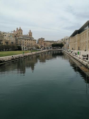 a river in the middle of a city with buildings at Old refurbished Apartment in Bormla in Cospicua