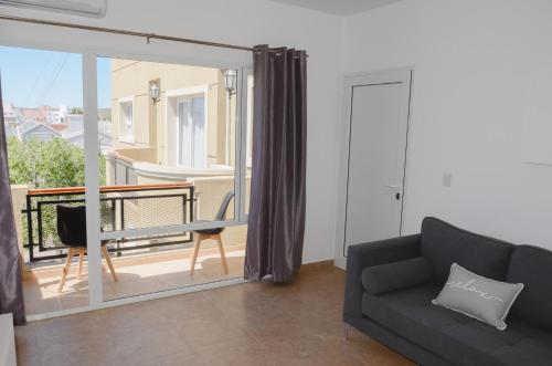 sala de estar con sofá y vistas a un balcón en Linea Recta Sur- Huemul, departamento amplio, de 3 dormitorios a pasos del mar, en Puerto Madryn