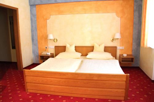 a bedroom with a large bed with white sheets and pillows at Hotel-Garni Goldener Schwan in Bad Windsheim