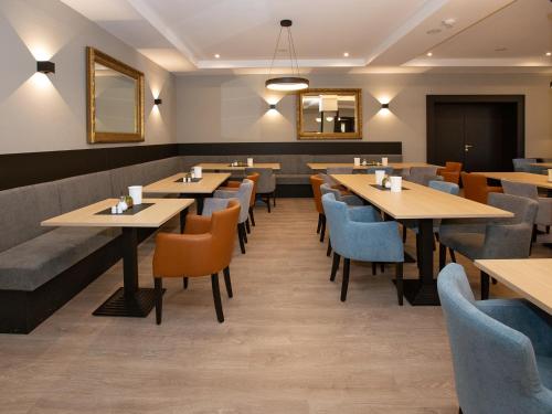 a restaurant with wooden tables and blue chairs at DORMERO Hotel Worms in Worms
