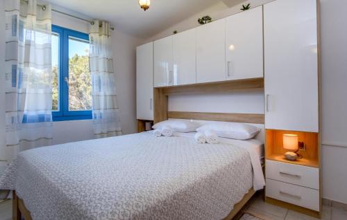 a bedroom with a bed with white cabinets and a window at 1 Bedroom Amazing Home In Cunski in Cunski