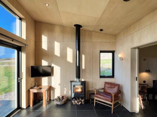 a living room with a fireplace and a chair at Tillyfruskie Farm Cabin in Banchory