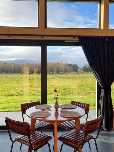 a table and chairs in a room with a large window at Tillyfruskie Farm Holiday Cabin, Finzean in Banchory
