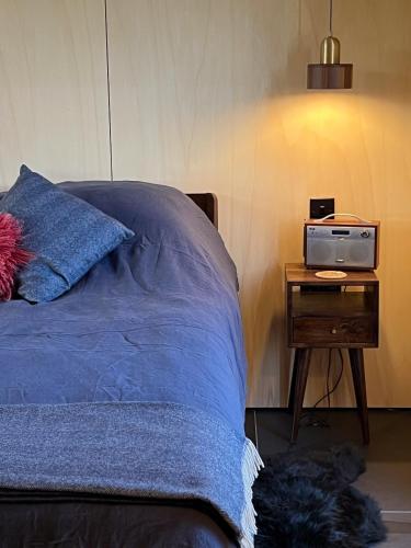 a bedroom with a bed and a nightstand with a radio at Tillyfruskie Farm Holiday Cabin, Finzean in Banchory