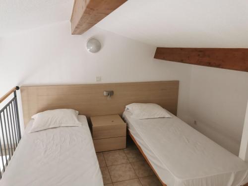 2 łóżka pojedyncze w pokoju ze schodami w obiekcie Terres de France - Les Hauts du Maquis w mieście Linguizzetta