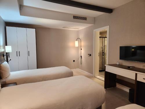a hotel room with two beds and a flat screen tv at Lulubay Rooms & Suites in Kusadası
