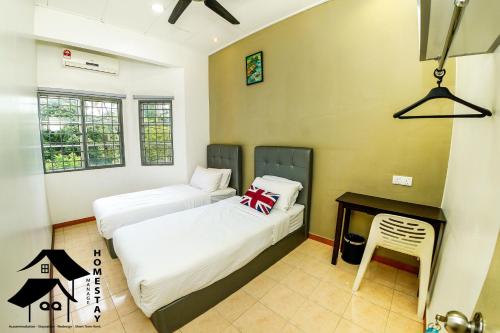 two beds in a room with a table and a chair at QQSweetHomeLovelyBktChedang10bedroom Homestay (15-17pax) in Seremban