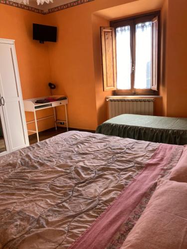 an orange room with two beds and a window at B&B da Paola in Bardalone