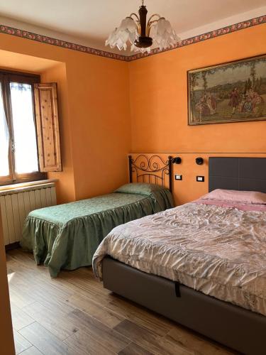 two beds in a room with orange walls at B&B da Paola in Bardalone