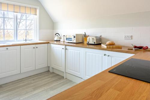 a kitchen with white cabinets and a laptop on a counter at 4 Truman Lodge in Thorpeness
