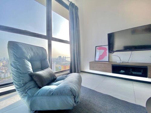 a blue chair in a living room with a large window at Urban Suites #High floor view #Infinity Pool #Georgetown #4pax #2BR 2bath #2 Queen #Quality well maintained #Private host in Jelutong
