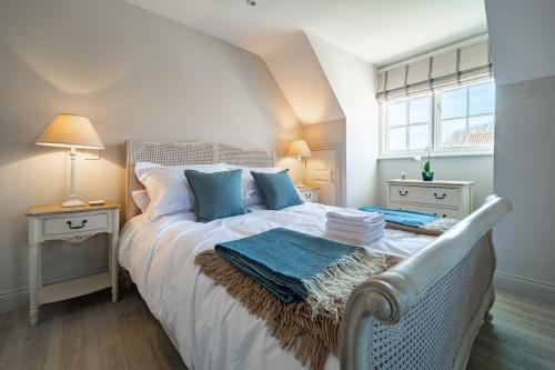 a bedroom with a bed with white sheets and blue pillows at 4 Truman Lodge in Thorpeness