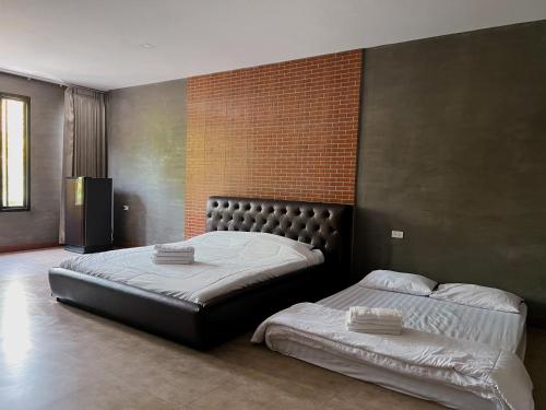 a bedroom with two beds and a brick wall at Manee Poolvilla in Khanom