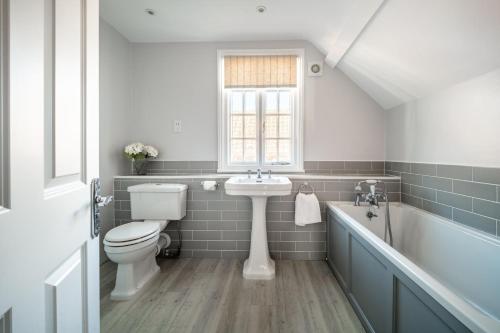 a bathroom with a sink and a toilet and a tub at 4 Truman Lodge in Thorpeness