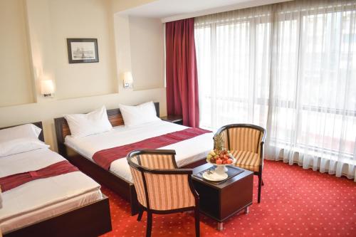 a hotel room with two beds and a table and chairs at Hotel Hamburg in Skopje