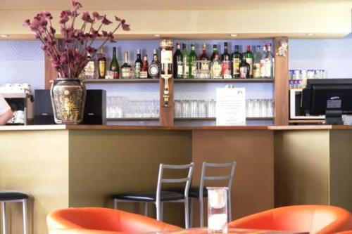 a bar with a counter with chairs and bottles of alcohol at Kurhotel Pyramide AG in Bad Windsheim