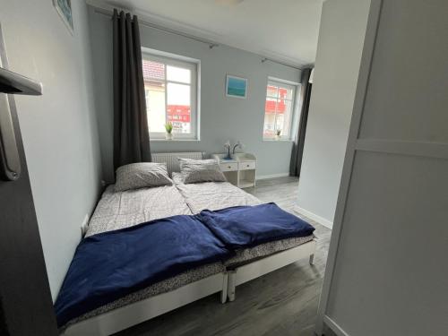 a bedroom with a bed with a blue blanket on it at Apartament Hugo in Świnoujście