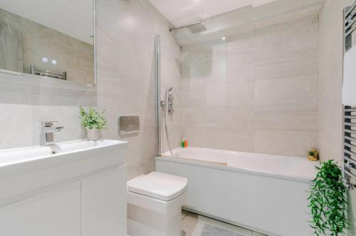 a bathroom with a toilet and a tub and a sink at 1-Bed in Bricklane Shoreditch - 5 Sleeps in London