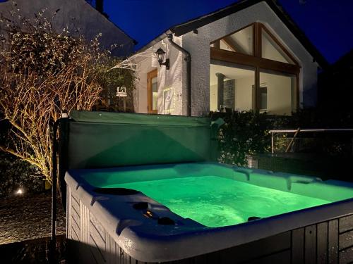 una bañera de hidromasaje frente a una casa por la noche en Fox Corner, Ambleside, romantic retreat for two, dog friendly, hot tub en Ambleside