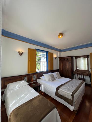 Una habitación de hotel con dos camas y una ventana. en Pousada Sinhá Olímpia, en Ouro Preto