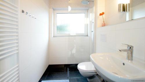 a bathroom with a sink and a toilet and a window at Gaestehaus-Achtern-Diek-Wohnung-12 in Süderhöft