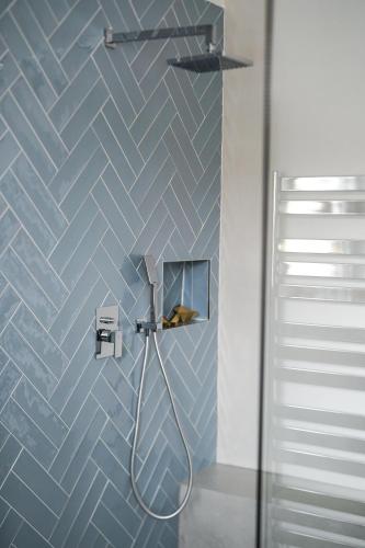 a bathroom with a shower with blue tiles at Apartmán v centru in Šumperk