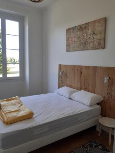 une chambre avec un lit avec une tête de lit en bois et une fenêtre dans l'établissement Les Logis du Hallay, à La Haie-Fouassière