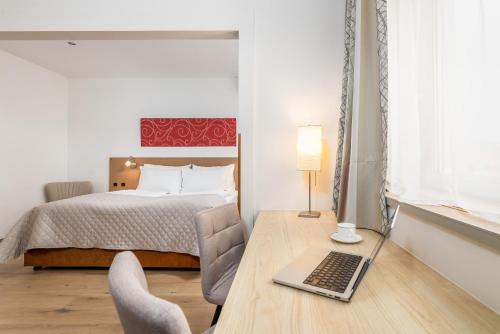 a bedroom with a bed and a desk with a laptop at Hotel Zentral in Wiener Neustadt