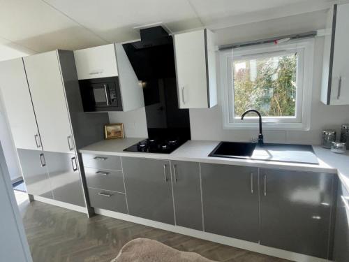 a kitchen with white cabinets and a sink and a window at Modern homely Chalet in Tuxford in Askham