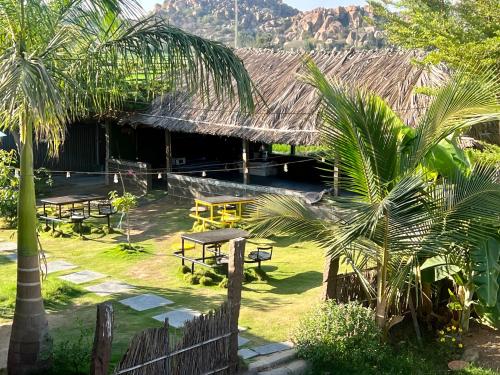 a building with a table and benches in front of it at Hippie Land Nature Stay in Hampi
