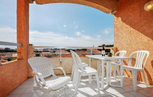 d'une terrasse avec des chaises blanches, une table et une vue. dans l'établissement Nice Apartment In Canet-En-Roussillon, à Canet