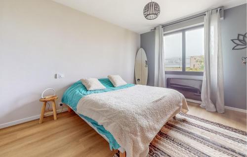 1 Schlafzimmer mit einem Bett, einem Fenster und einem Surfbrett in der Unterkunft Gorgeous Home In Bretignolles-sur-mer With House A Panoramic View in Brétignolles-sur-Mer