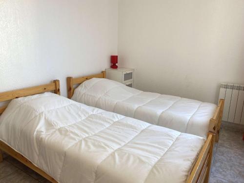 deux lits dans une chambre avec des draps blancs dans l'établissement Confortable T2 avec terrasse privée près des Thermes et du centre-ville à Balaruc-les-Bains - FR-1-553-144, à Balaruc-les-Bains