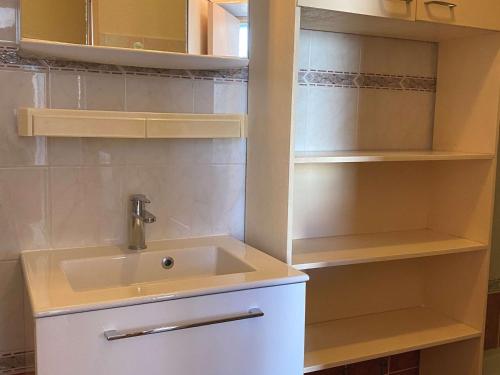 La salle de bains blanche est pourvue d'un lavabo et d'étagères. dans l'établissement Confortable T2 avec terrasse privée près des Thermes et du centre-ville à Balaruc-les-Bains - FR-1-553-144, à Balaruc-les-Bains