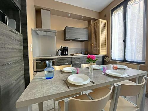 d'une cuisine avec une table avec des assiettes et des fleurs. dans l'établissement Triplex Charmant T4, 60m², 3 Chambres, Cœur de Berck Plage, Proche Commerces et Plage - FR-1-646-21, à Berck-sur-Mer