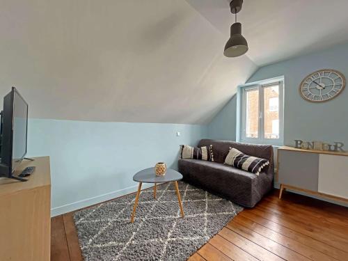 un salon avec un canapé et une horloge au mur dans l'établissement Studio rénové cœur centre-ville, tout confort avec wifi, TV et lave-linge, proche commerces - Berck - FR-1-646-15, à Berck-sur-Mer