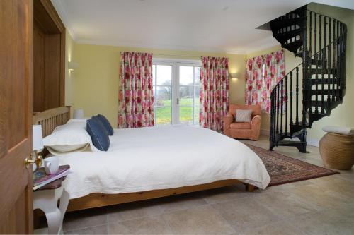 a bedroom with a white bed and a staircase at Ty Cellin Swyddffynnon in Ystrad-Meurig