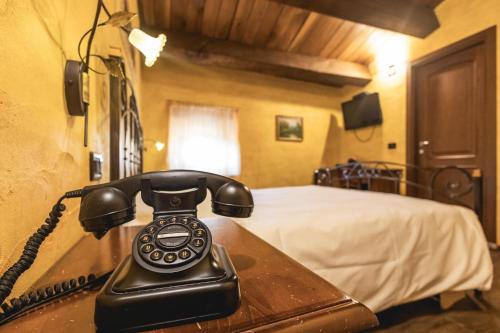 un teléfono sentado en una mesa de madera en un dormitorio en Locanda dell'Ambra - Eleganza Rustica nel cuore della Romagna en Talamello