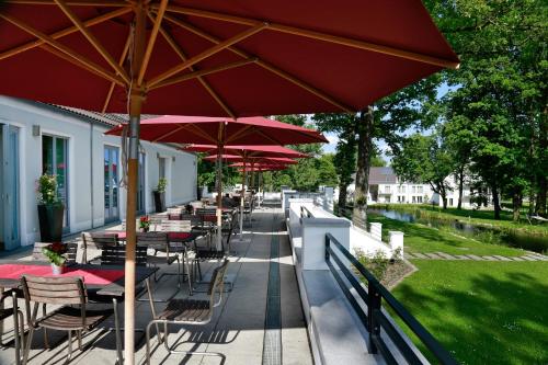a row of tables and chairs with red umbrellas at B&O Parkhotel in Bad Aibling