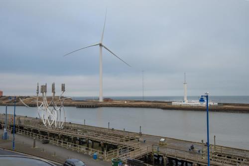 a view of a pier with a windmill in the water at The Commissioners Quay Inn - The Inn Collection Group in Blythe