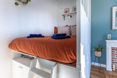- une chambre dotée d'un lit avec des draps orange et des murs bleus dans l'établissement Ruby Magenta, à Paris