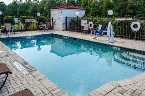 a swimming pool at a resort with chairs and a fence at Spark by Hilton Savannah Airport in Savannah