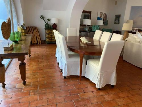 een eetkamer met een tafel en witte stoelen bij Villa Bianca in Porto Ercole