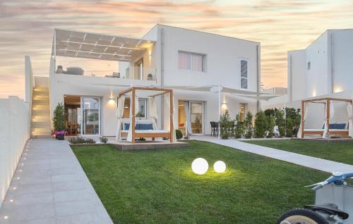 ein weißes Haus mit Licht auf dem Rasen in der Unterkunft Cozy Home In Marina Di Ragusa With Wifi in Marina di Ragusa