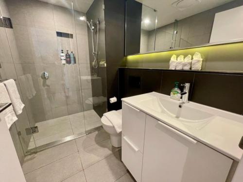 a bathroom with a shower and a sink and a toilet at Modern Homely 2BR APT w Parking Bowen Hills in Brisbane