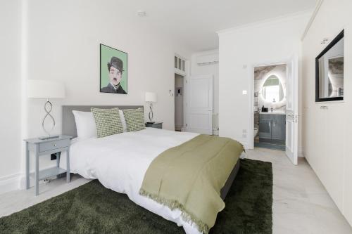 a white bedroom with a large bed with a green rug at Luxury 2 Bedrooms Apartment in South Kensington in London
